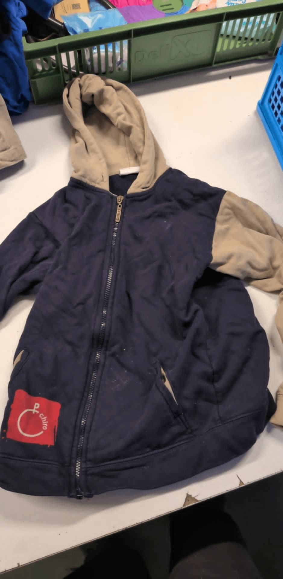 a blue jacket with a red c on the front sits on a table