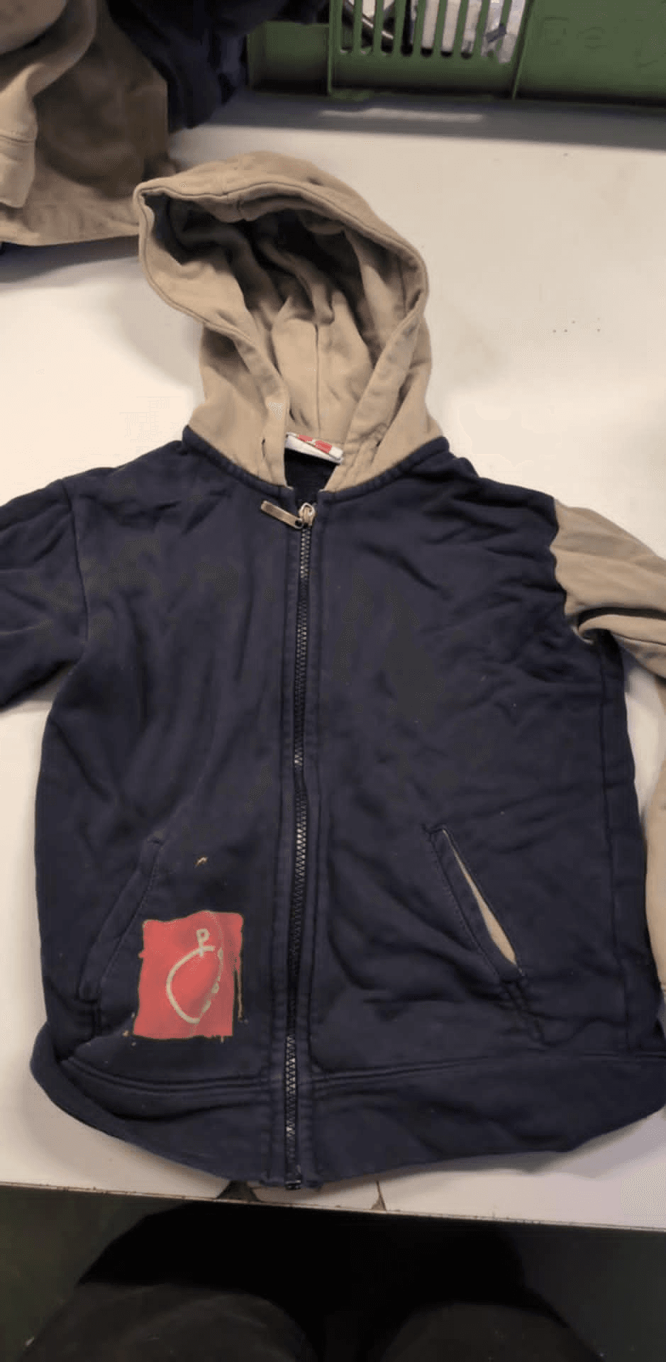 a blue and tan hoodie with a red patch on it